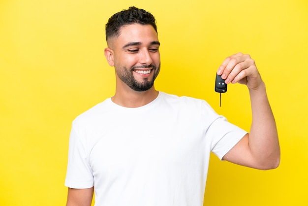 Young Arab man holding car keys isolated on yellow background with happy expression