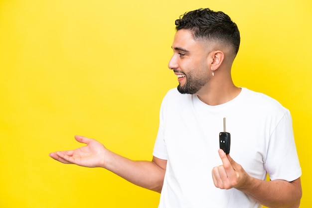 Young Arab man holding car keys isolated on yellow background with surprise facial expression