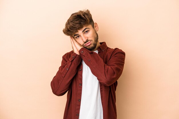 Young arab man isolated on beige background yawning showing a tired gesture covering mouth with hand.