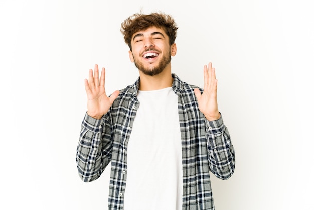 Young arab man laughs out loudly keeping hand on chest.