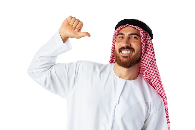 Young Arab man in traditional clothing pointing on himself on white background