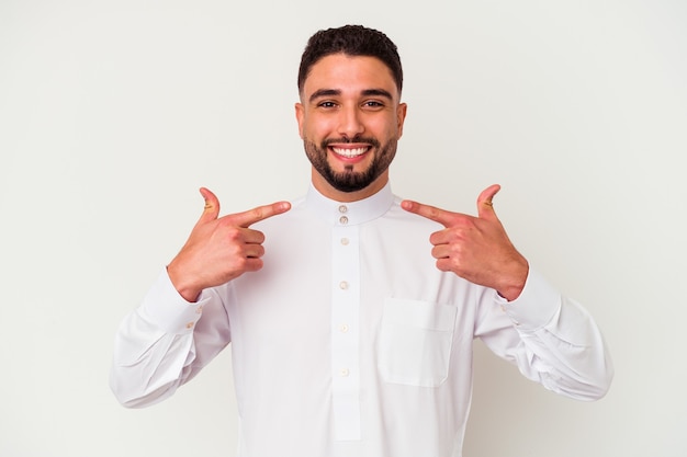 Young arab man wearing typical arab clothes isolated on white background smiles, pointing fingers at mouth.