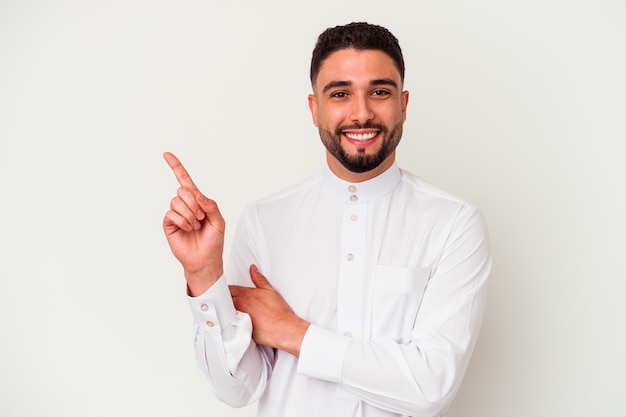 Photo young arab man wearing typical arab clothes isolated on white background smiling cheerfully pointing with forefinger away.