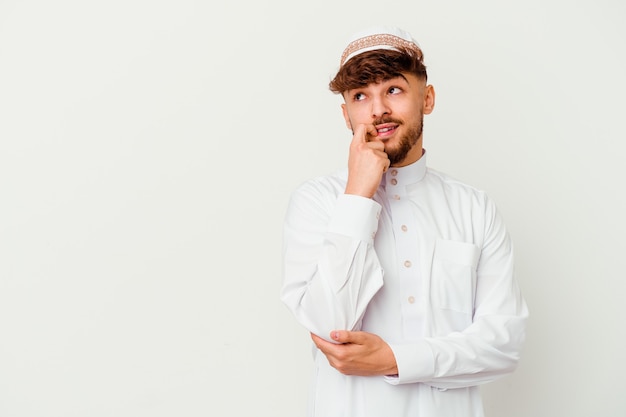 Young Arab man wearing the typical arabic costume isolated on white relaxed thinking about something looking at a copy space.