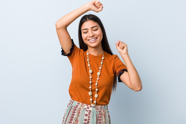 Young arab woman celebrating a special day, jumps and raise arms with energy.