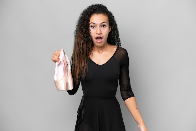 Young Arab woman dancing ballet isolated on grey background with surprise facial expression