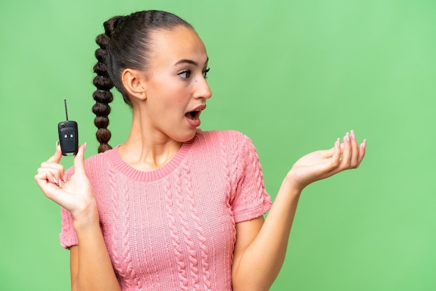 Young Arab woman holding car keys over isolated background with surprise facial expression