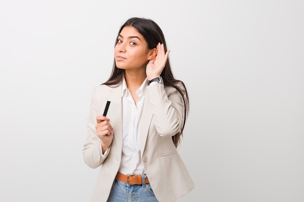 Young arab woman holding a credit card trying to listening a gossip.