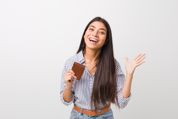 Young arab woman holding a wallet celebrating a victory or success