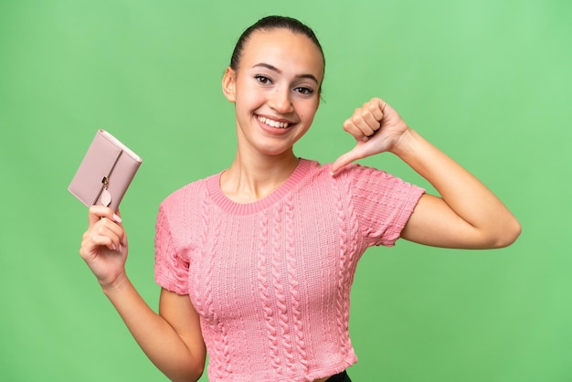 Young Arab woman holding a wallet over isolated background proud and selfsatisfied