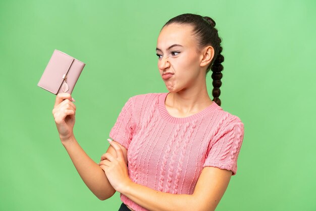 Young Arab woman holding a wallet over isolated background with sad expression