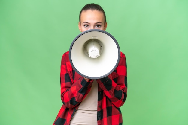 Young Arab woman over isolated background shouting through a megaphone to announce something