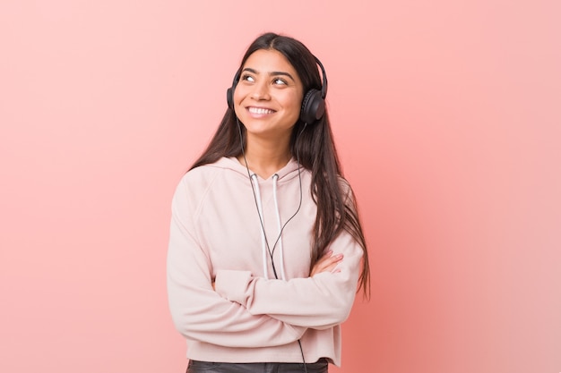 Young arab woman listening to music smiling confident with crossed arms.