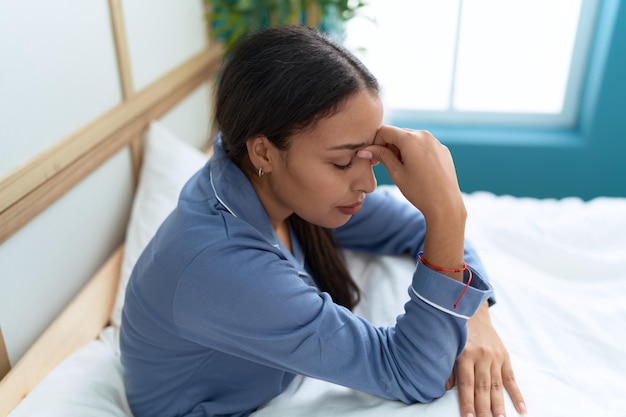 Young arab woman stressed sitting on bed at bedroom