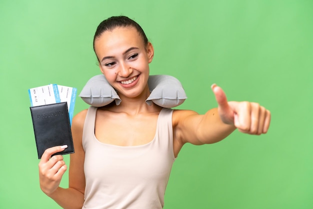 Young Arab woman with Inflatable Travel Pillow over isolated background giving a thumbs up gesture