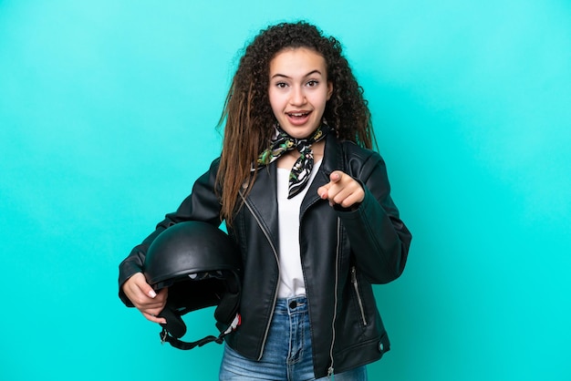 Young Arab woman with a motorcycle helmet isolated on blue background surprised and pointing front