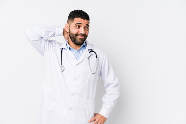 Young arabian doctor man isolated touching back of head, thinking and making a choice.