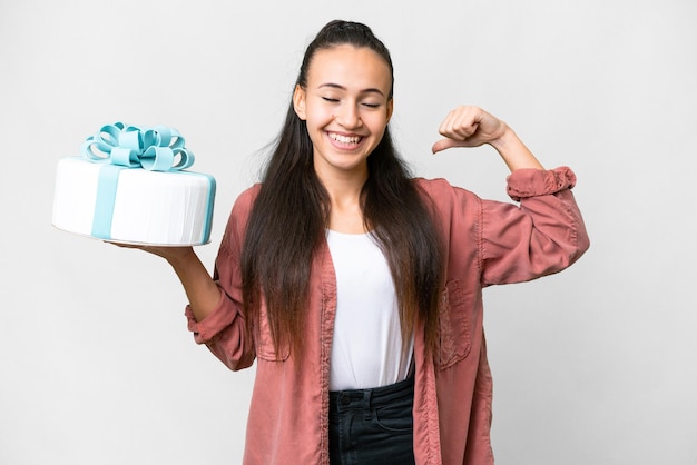 Young Arabian woman holding birthday cake over isolated white background doing strong gesture