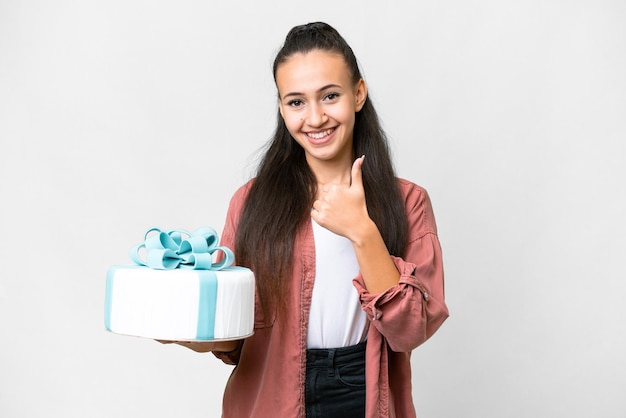 Young Arabian woman holding birthday cake over isolated white background giving a thumbs up gesture