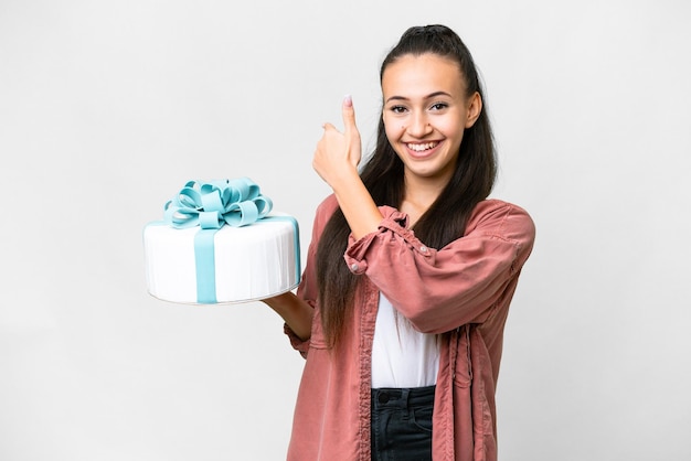 Young Arabian woman holding birthday cake over isolated white background pointing back