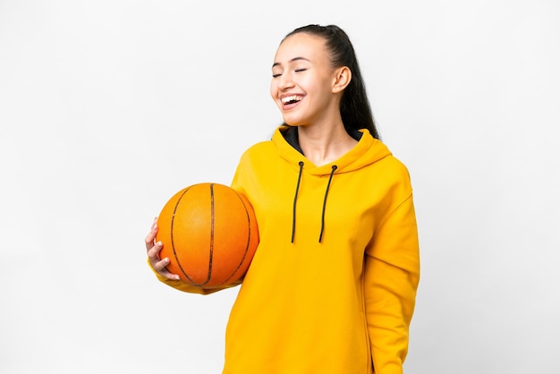 Young Arabian woman playing basketball over isolated white background laughing in lateral position