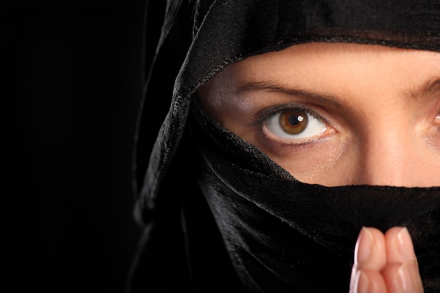 a young arabic woman focused on her prayer over black