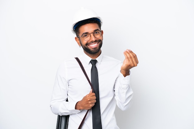 Young architect Brazilian man with helmet and holding blueprints isolated on white background making money gesture