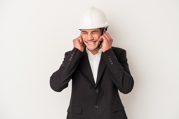 Young architect caucasian man isolated on white background covering ears with hands.