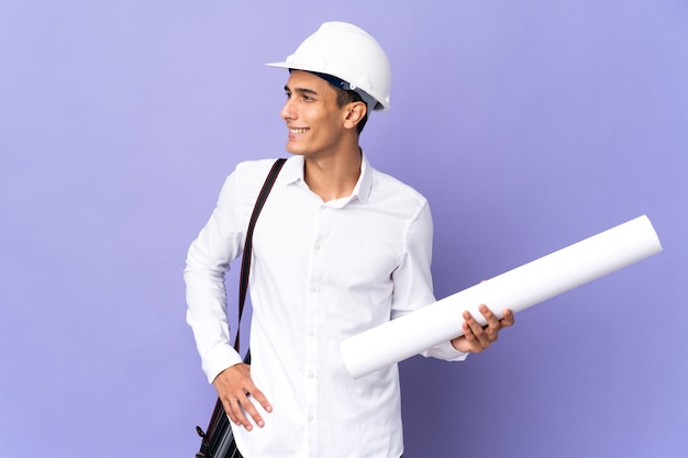 Young architect man isolated on background posing with arms at hip and smiling