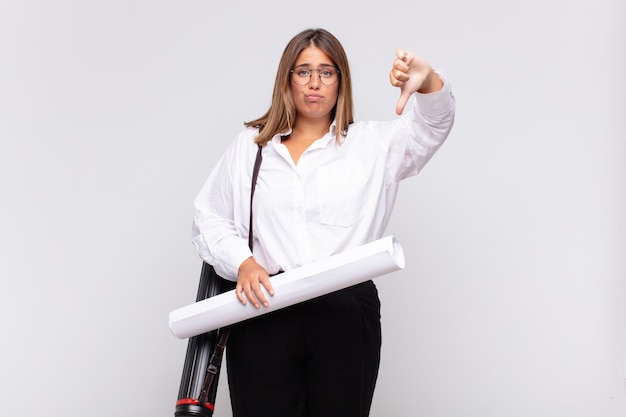 young architect woman feeling cross, angry, annoyed, disappointed or displeased, showing thumbs down with a serious look