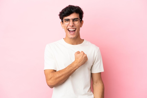 Young Argentinian man isolated on pink background celebrating a victory