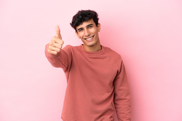 Young Argentinian man isolated on pink background with thumbs up because something good has happened