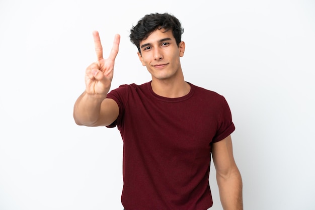 Young Argentinian man isolated on white background smiling and showing victory sign