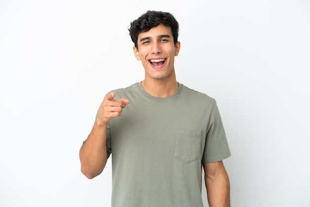 Young Argentinian man isolated on white background surprised and pointing front