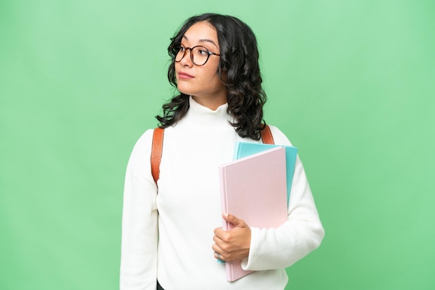 Young Argentinian student woman over isolated background looking to the side