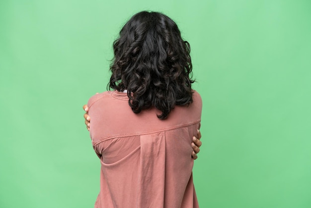 Young Argentinian woman over isolated background in back position