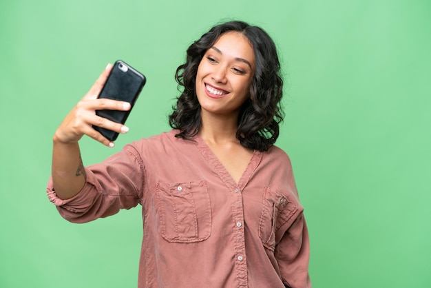 Young Argentinian woman over isolated background making a selfie