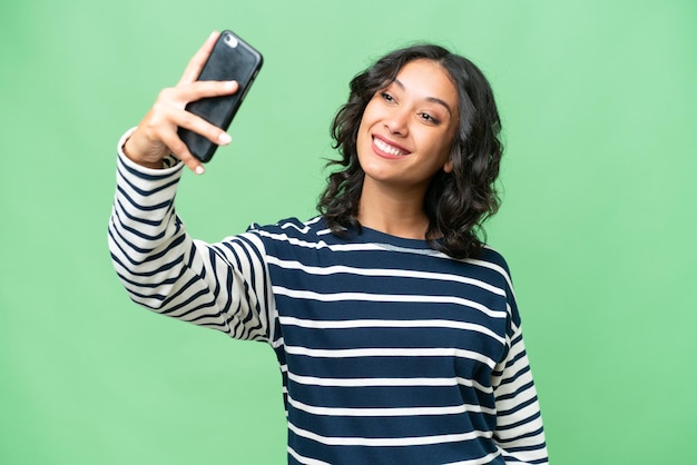 Young Argentinian woman over isolated background making a selfie