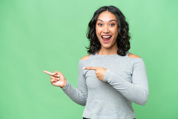 Young Argentinian woman over isolated background surprised and pointing side