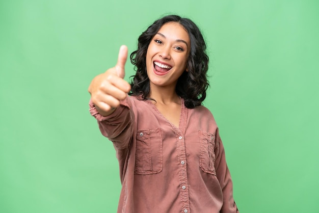 Young Argentinian woman over isolated background with thumbs up because something good has happened