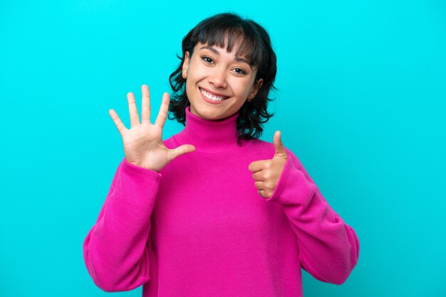 Young Argentinian woman isolated on blue background counting six with fingers