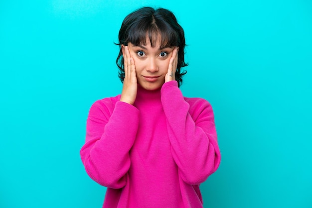 Young Argentinian woman isolated on blue background frustrated and covering ears