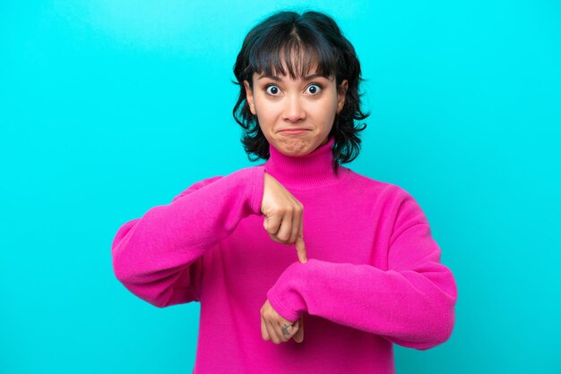 Young Argentinian woman isolated on blue background making the gesture of being late