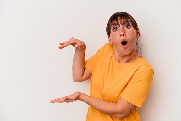 Young Argentinian woman isolated on white background shocked and amazed holding a copy space between hands.