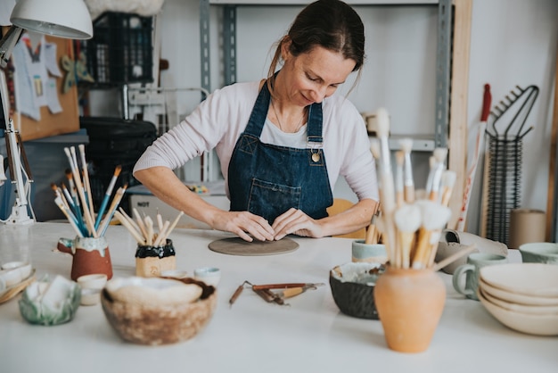 Young artisan woman working with her hand a piece of ceramic focus on person