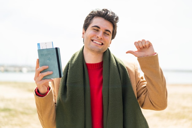 Young artist caucasian man holding a palette isolated on red background pointing front with happy expression