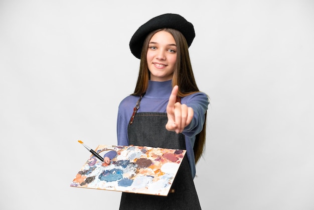 Young artist man holding a palette over isolated white background showing and lifting a finger