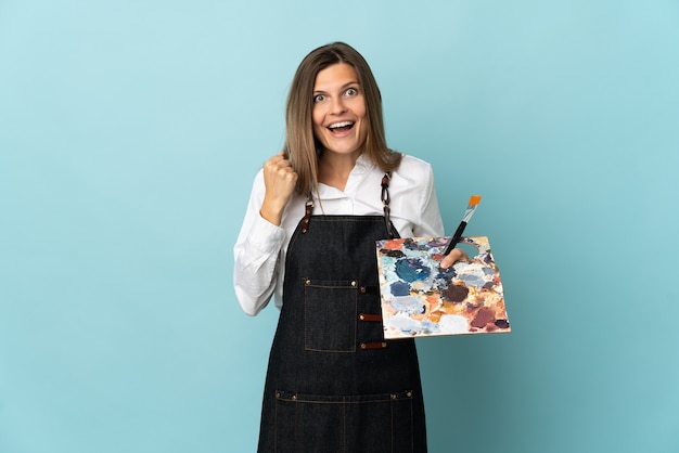 Young artist Slovak woman isolated on blue background celebrating a victory in winner position