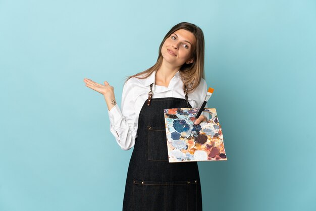 Young artist Slovak woman isolated on blue wall extending hands to the side for inviting to come