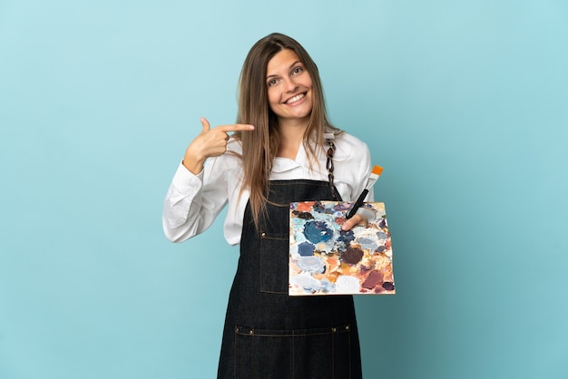 Young artist Slovak woman isolated on blue wall giving a thumbs up gesture